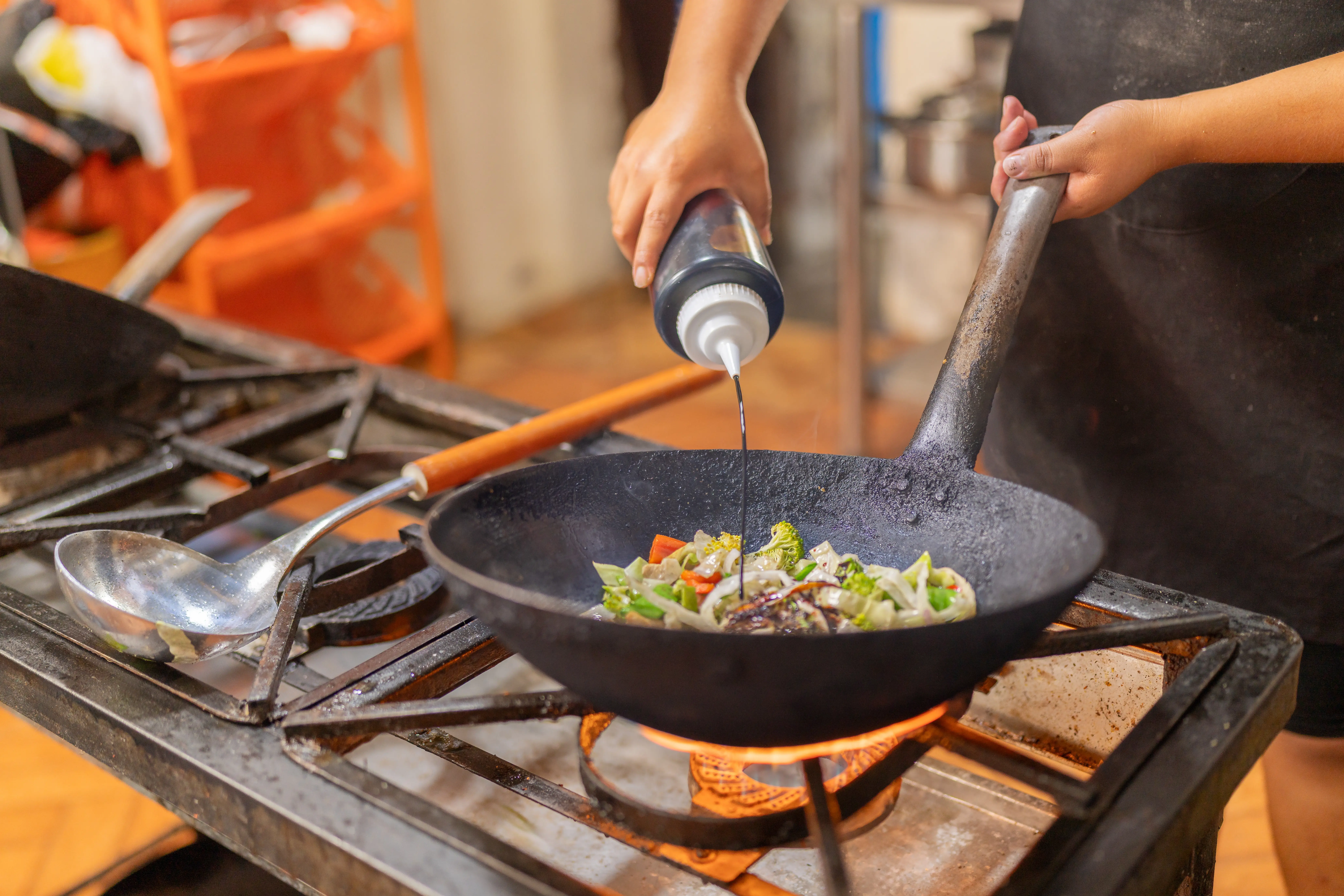 chef-adding-soy-sauce-to-vegetables-in-a-pan-2025-03-05-08-55-45-utc