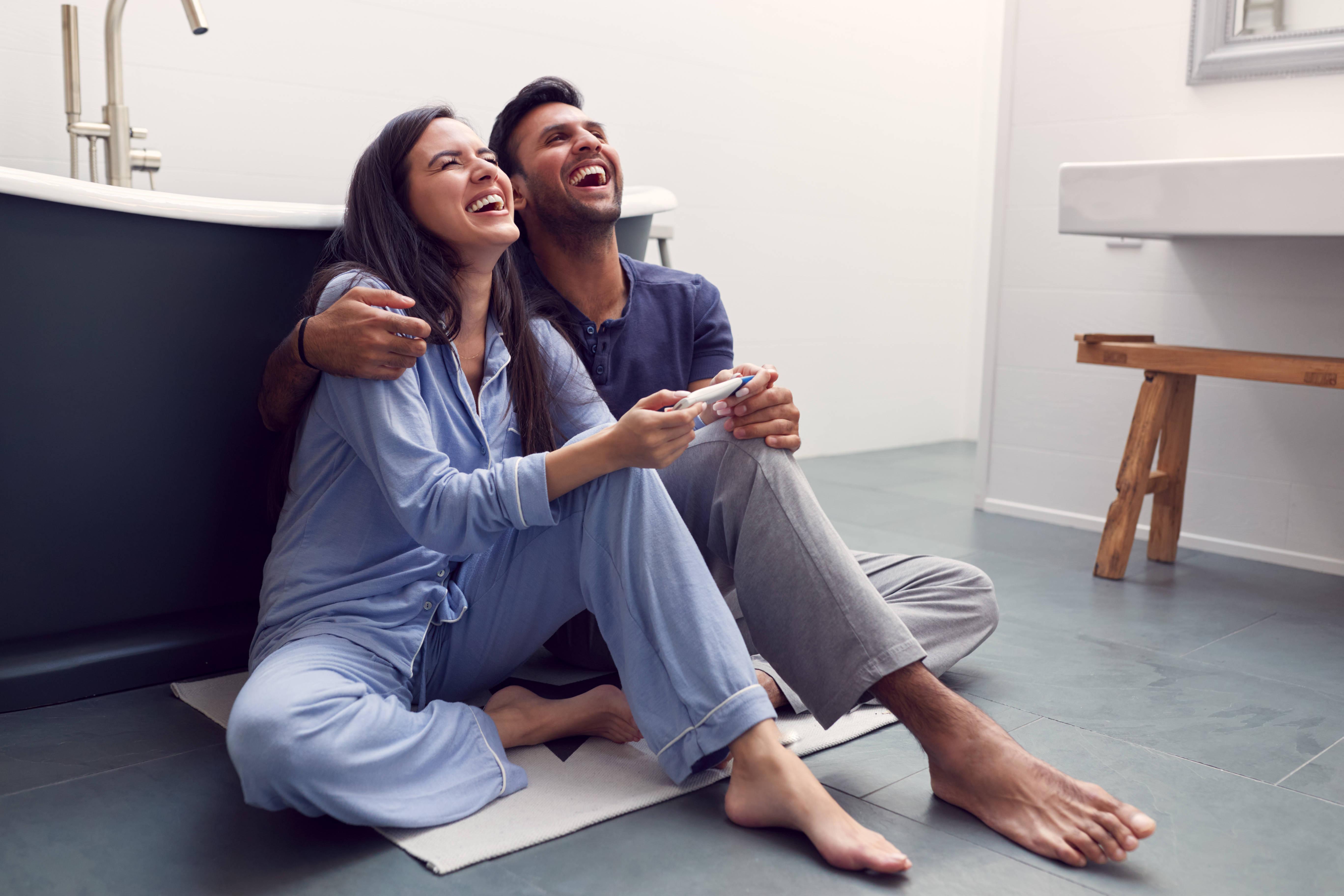 excited-couple-sitting-on-floor-in-bathroom-at-hom-2024-10-19-10-54-55-utc