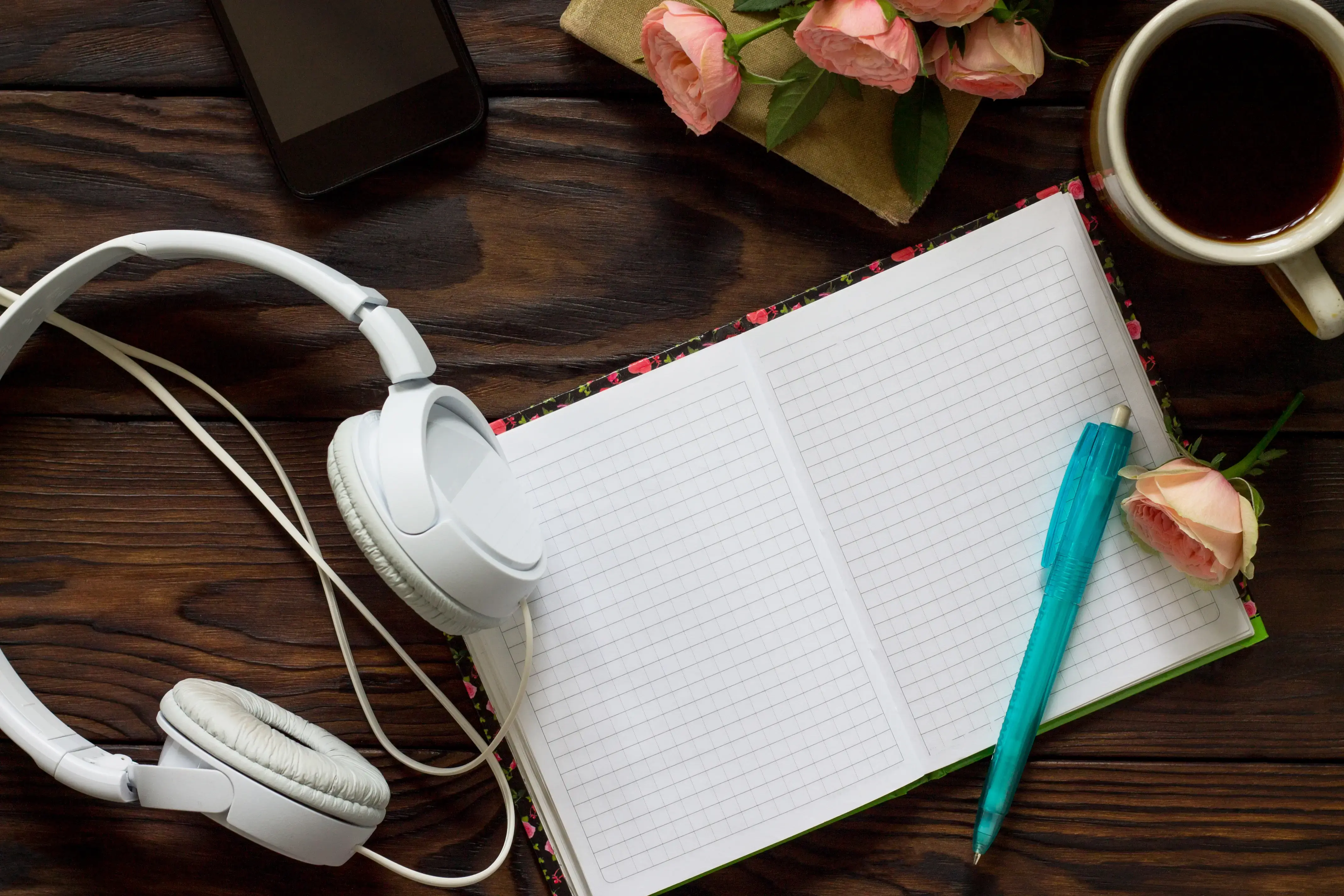smartphone-headphones-and-open-notebook-with-blan-2025-03-07-14-21-05-utc